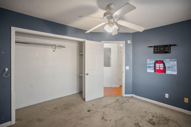 unfurnished bedroom with light carpet, ceiling fan, a closet, a textured ceiling, and electric panel