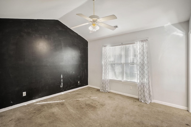 empty room featuring lofted ceiling, ceiling fan, and carpet flooring