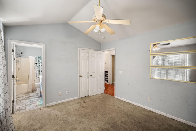 unfurnished bedroom with connected bathroom, light carpet, a closet, vaulted ceiling, and ceiling fan