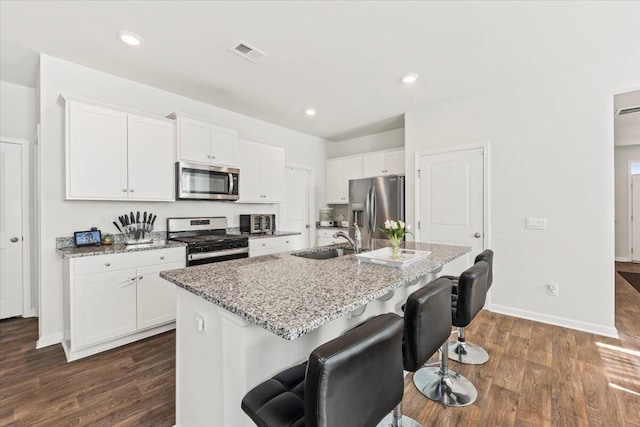 kitchen with appliances with stainless steel finishes, sink, an island with sink, and white cabinets