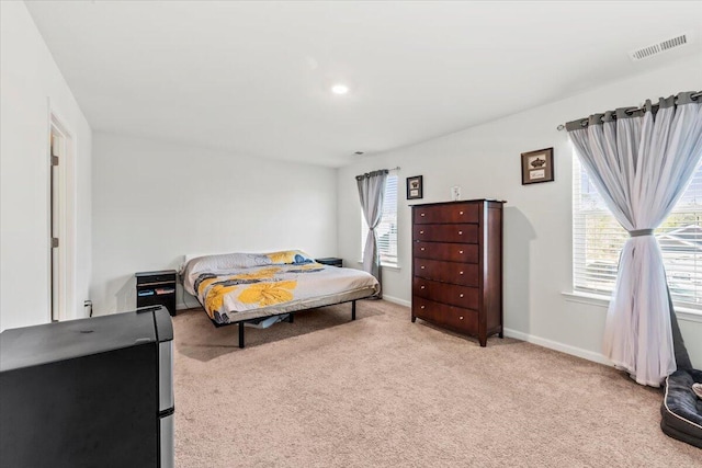 bedroom featuring light carpet and multiple windows