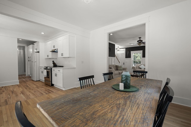 dining area featuring ceiling fan, light wood-style floors, baseboards, recessed lighting, and stairs
