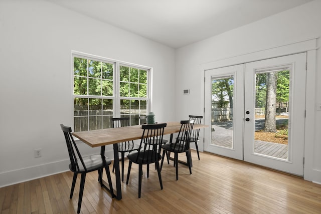 dining room featuring french doors, light wood finished floors, and baseboards
