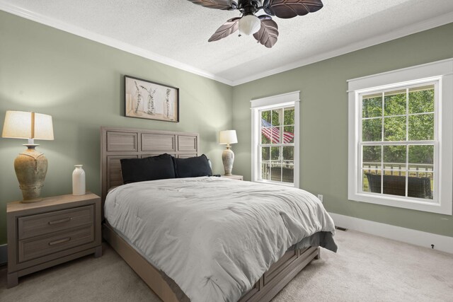bedroom with ornamental molding, light colored carpet, a textured ceiling, and a ceiling fan