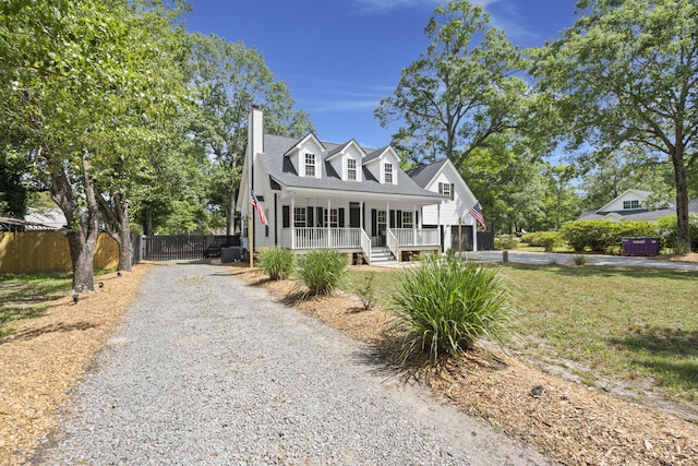 new england style home with driveway, covered porch, and a chimney