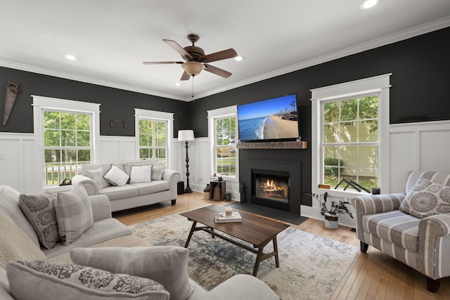 living room featuring a decorative wall, a fireplace with flush hearth, wood finished floors, a ceiling fan, and recessed lighting
