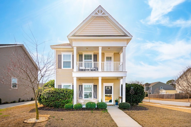 view of front of house featuring a front yard, a balcony, and covered porch