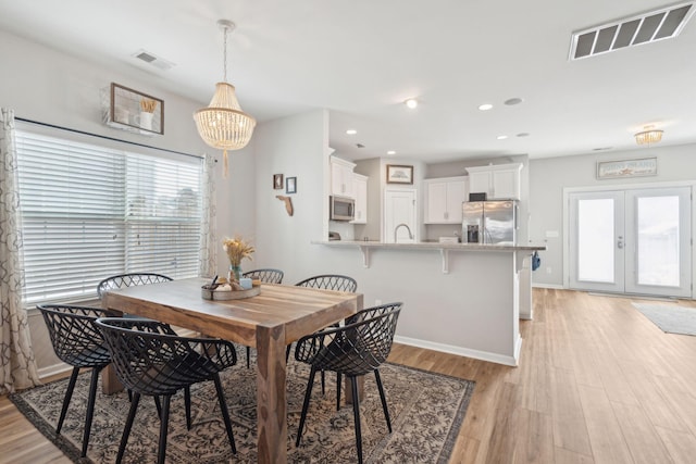 dining space with a notable chandelier, light hardwood / wood-style floors, and french doors