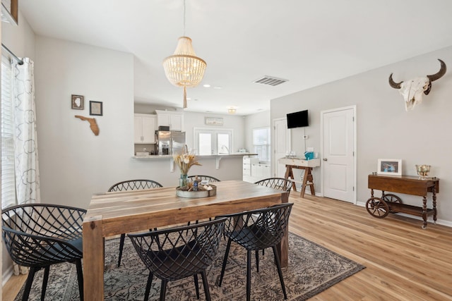 dining area with an inviting chandelier and light hardwood / wood-style floors