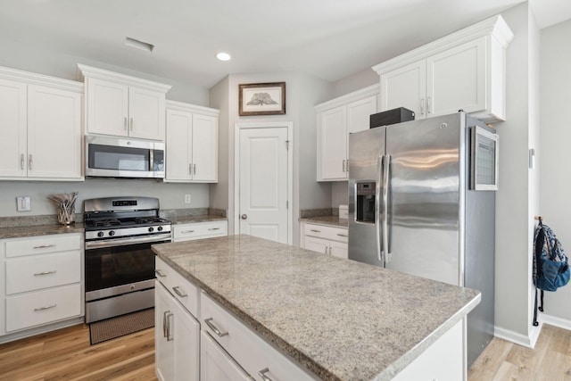 kitchen featuring white cabinetry, light wood-type flooring, a center island, and appliances with stainless steel finishes