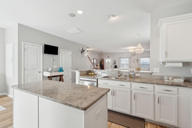 kitchen featuring white cabinetry, sink, stainless steel dishwasher, and a center island