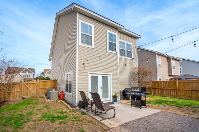 rear view of property with french doors, cooling unit, a lawn, and a patio area