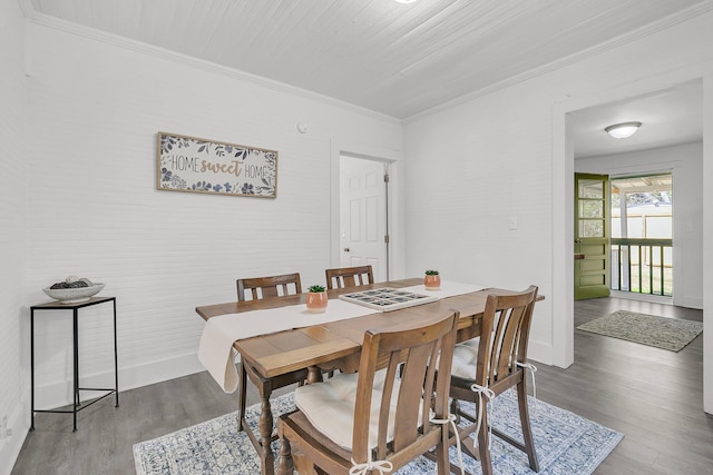 dining room featuring crown molding, baseboards, and wood finished floors