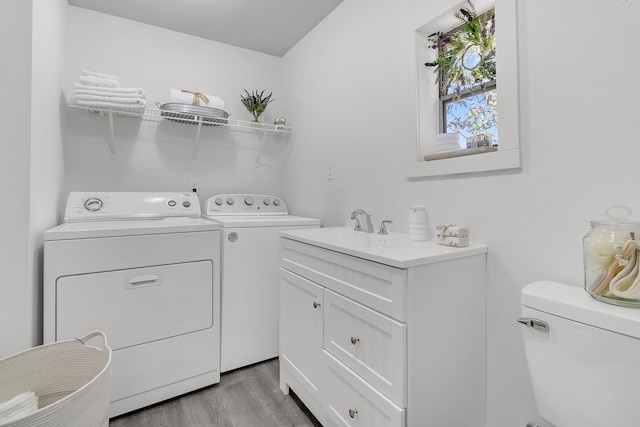 clothes washing area with laundry area, washing machine and dryer, light wood finished floors, and a sink