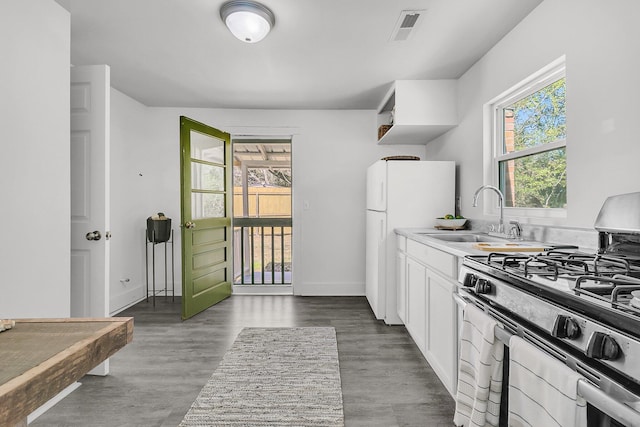 kitchen with visible vents, a sink, freestanding refrigerator, white cabinets, and stainless steel gas range