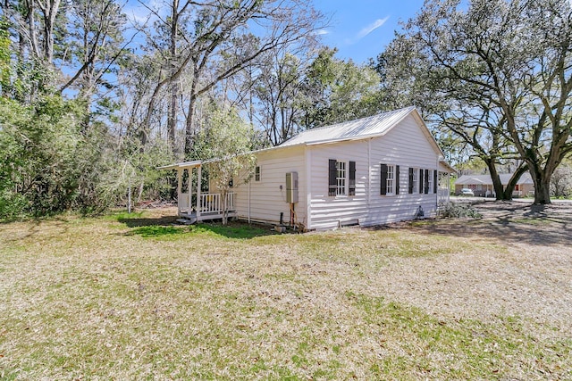 view of side of home with a lawn and metal roof