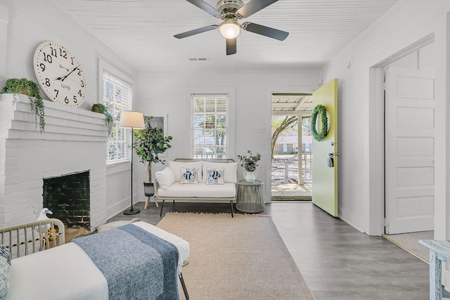 bedroom featuring wood finished floors, visible vents, ceiling fan, access to exterior, and a brick fireplace