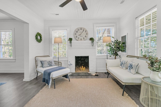 living area featuring a ceiling fan, wood finished floors, a fireplace, and a healthy amount of sunlight