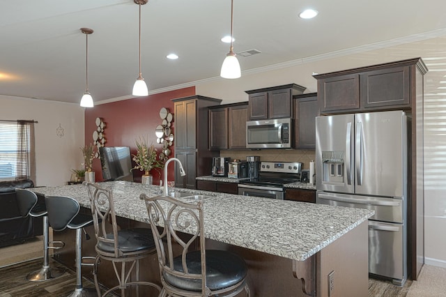 kitchen with dark brown cabinetry, visible vents, decorative backsplash, stainless steel appliances, and a sink