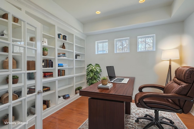 office space featuring built in shelves, a healthy amount of sunlight, and light hardwood / wood-style flooring