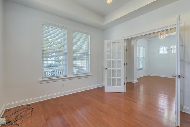 spare room with french doors, a chandelier, and hardwood / wood-style flooring