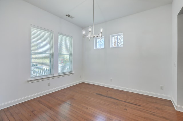 empty room featuring a wealth of natural light, a chandelier, and hardwood / wood-style floors