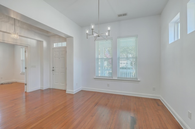 unfurnished dining area with an inviting chandelier and hardwood / wood-style flooring