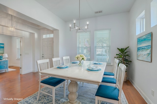 dining area with wood-type flooring and a chandelier