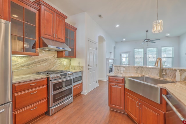 kitchen featuring pendant lighting, stainless steel appliances, decorative backsplash, sink, and ceiling fan