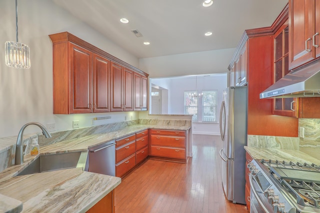 kitchen featuring pendant lighting, stainless steel appliances, an inviting chandelier, sink, and kitchen peninsula