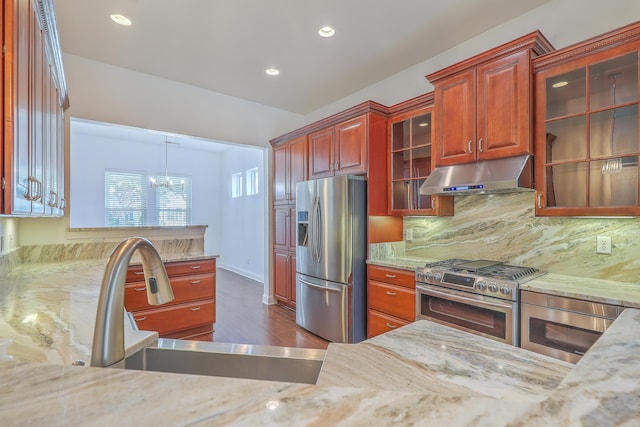 kitchen featuring appliances with stainless steel finishes, decorative backsplash, a chandelier, pendant lighting, and sink