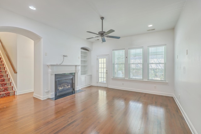 unfurnished living room with ceiling fan, hardwood / wood-style floors, and built in shelves