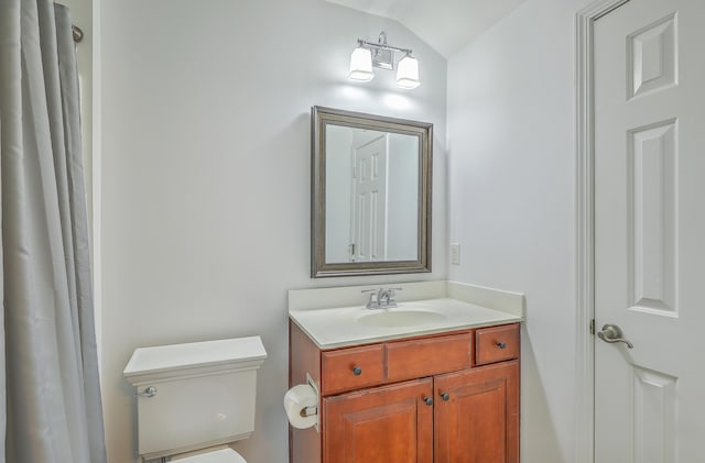 bathroom featuring toilet, vanity, and vaulted ceiling