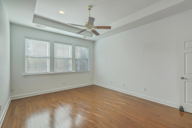 spare room with ceiling fan, hardwood / wood-style floors, and a raised ceiling