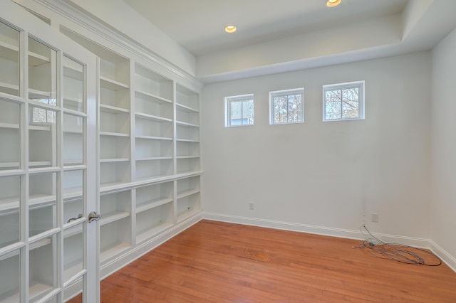 unfurnished room with hardwood / wood-style flooring, built in features, and a healthy amount of sunlight