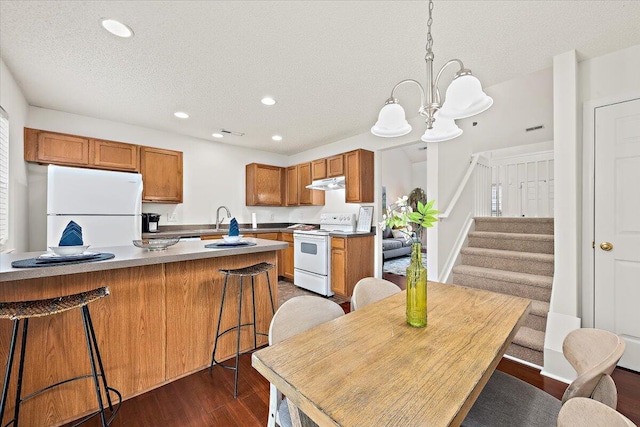 105 Brockman Way, Goose Creek, SC 29445 - kitchen featuring white appliances, under cabinet range hood, a textured ceiling, dark wood-type flooring, and a chandelier