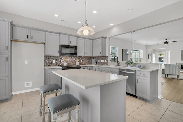 kitchen with a center island, decorative light fixtures, sink, and black appliances