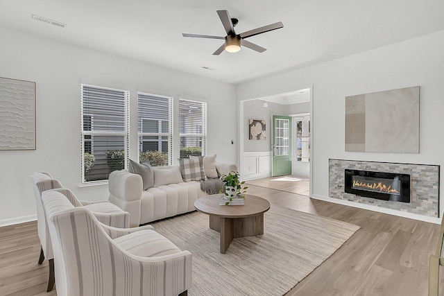 living room featuring light hardwood / wood-style flooring, ceiling fan, and a fireplace