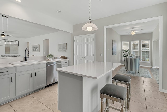 kitchen featuring dishwasher, decorative light fixtures, a center island, light tile patterned floors, and sink