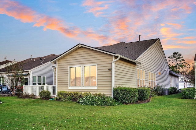 back house at dusk featuring a lawn