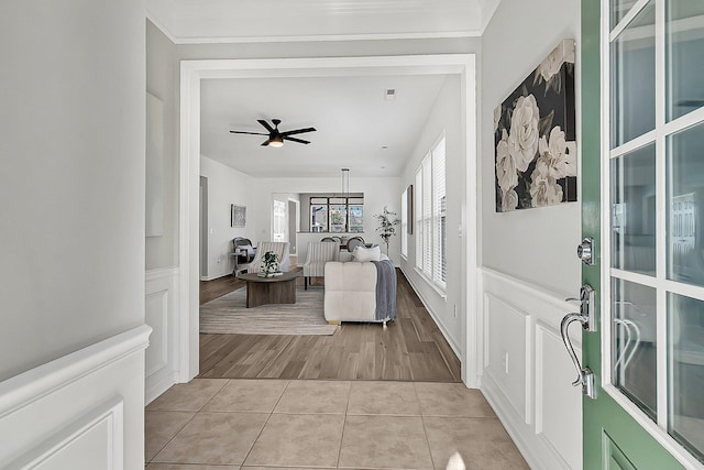 tiled entrance foyer with ceiling fan and crown molding