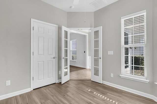 empty room with light hardwood / wood-style floors, french doors, ceiling fan, and plenty of natural light