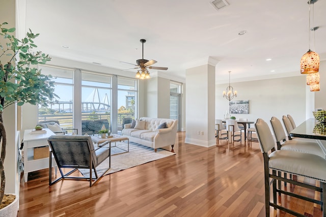 living room with crown molding, wood-type flooring, and ceiling fan with notable chandelier