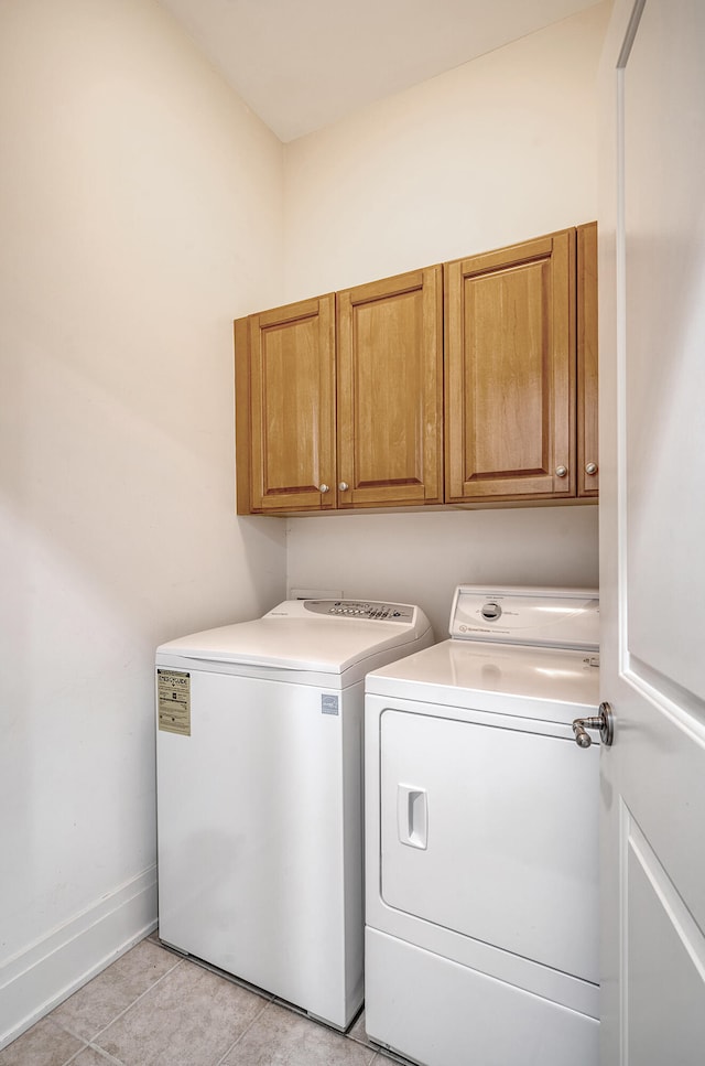 washroom with washer and dryer, light tile patterned floors, and cabinets