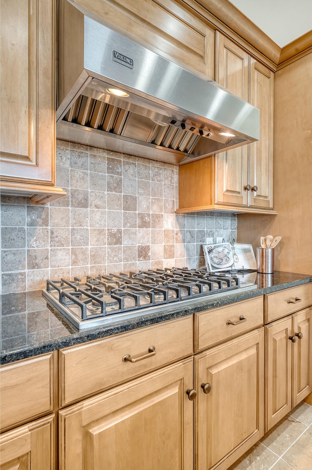 kitchen with stainless steel gas stovetop, decorative backsplash, ventilation hood, and dark stone counters