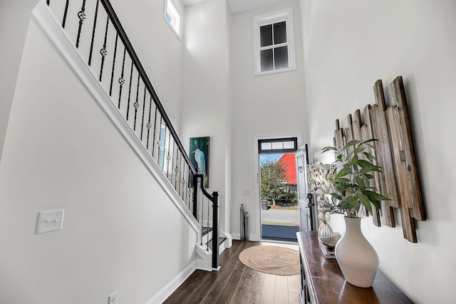 entryway with dark wood-type flooring, a wealth of natural light, baseboards, and stairway