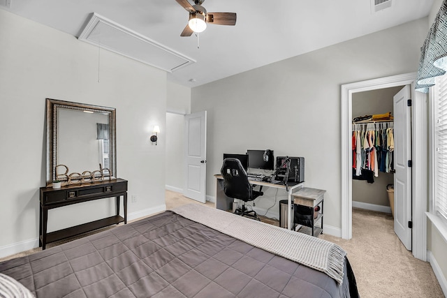 carpeted bedroom featuring a closet, attic access, a spacious closet, baseboards, and ceiling fan