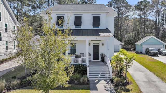 view of front of home featuring metal roof, a detached garage, a front yard, covered porch, and an outdoor structure