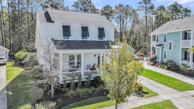 view of front of house with covered porch, driveway, a shingled roof, and metal roof