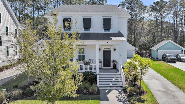 modern farmhouse featuring covered porch, an outdoor structure, a front lawn, metal roof, and a detached garage
